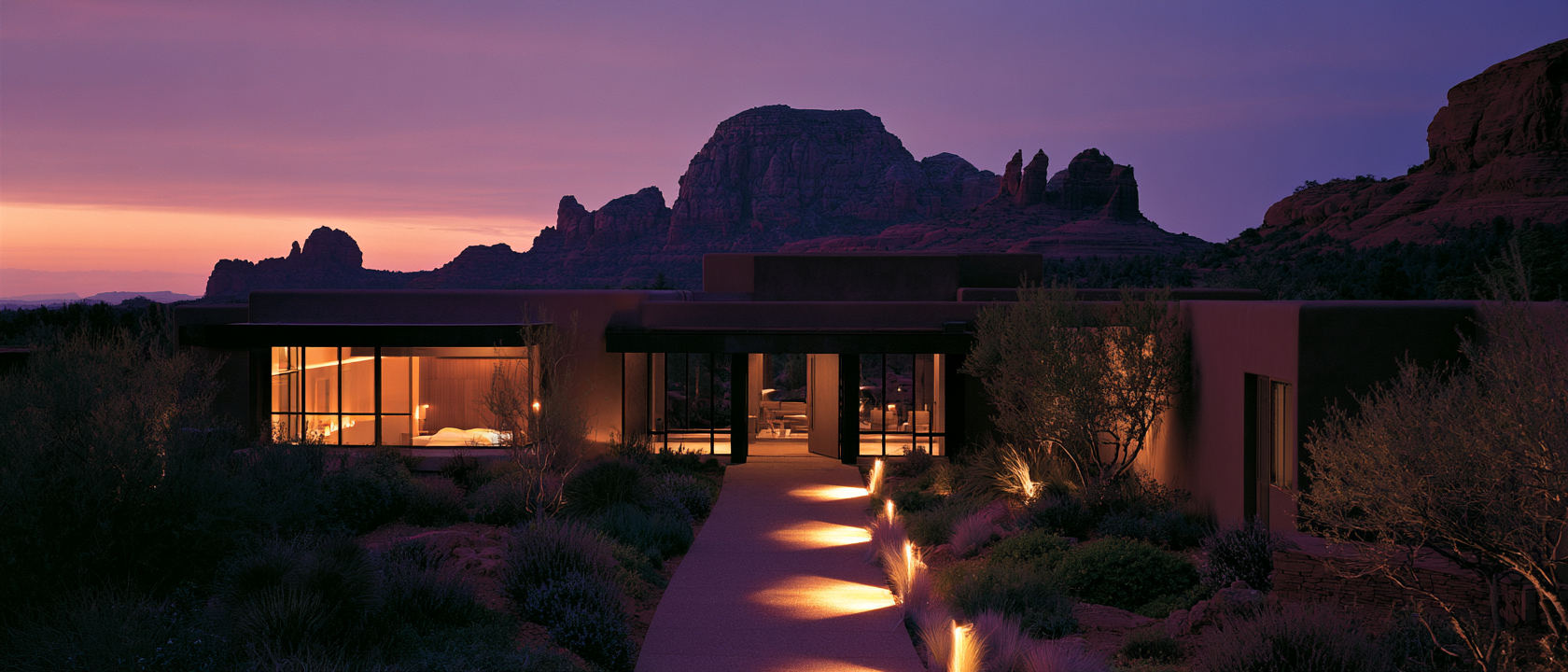 Wide establishing shot of a minimalist desert wellness property at twilight